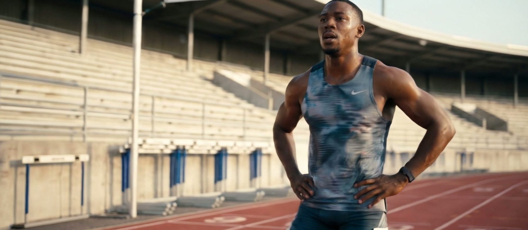 Athlete raising a forearm wearing the Hume Band 2.0 beside a running track